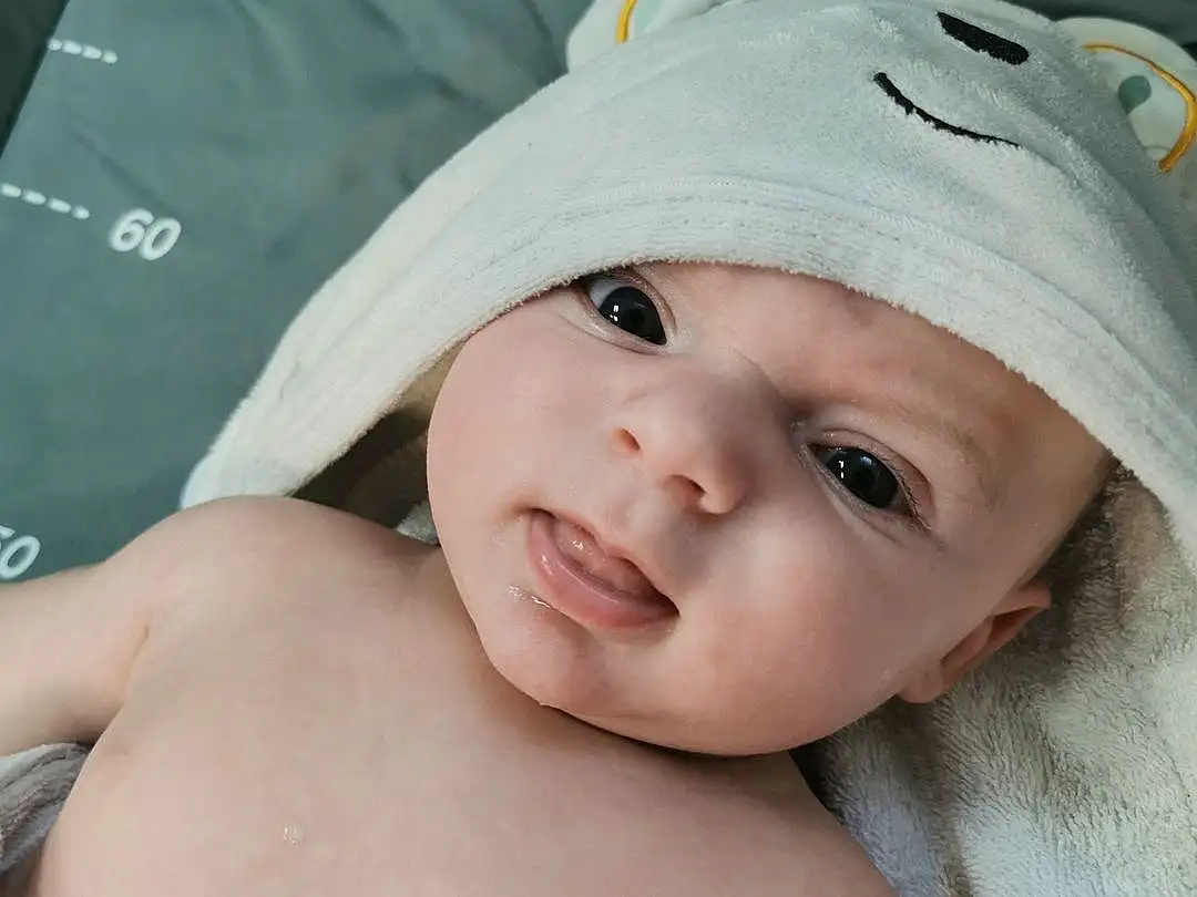 Joue, Lip, Sourire, Yeux, Eyebrow, Comfort, Baby, Happy, Bambin, Cap, Eyelash, Enfant, Chest, Linens, Fashion Accessory, Thumb, Portrait Photography, Abdomen, Stomach, Baby & Toddler Clothing, Personne, Headwear