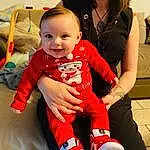 Head, Sourire, Happy, Sleeve, Baby & Toddler Clothing, Gesture, Bambin, Comfort, Red, Lap, People, Baby, Enfant, T-shirt, Event, Fun, Assis, Human Leg, Jewellery, Thumb, Personne, Joy