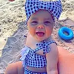 Sourire, Photograph, Bleu, Mouth, Light, Azure, Chapi Chapo, Plage, Textile, Body Of Water, Baby & Toddler Clothing, Happy, Headgear, Swimwear, Rose, Sand, Leisure, Thigh, Bambin, Personne, Headwear