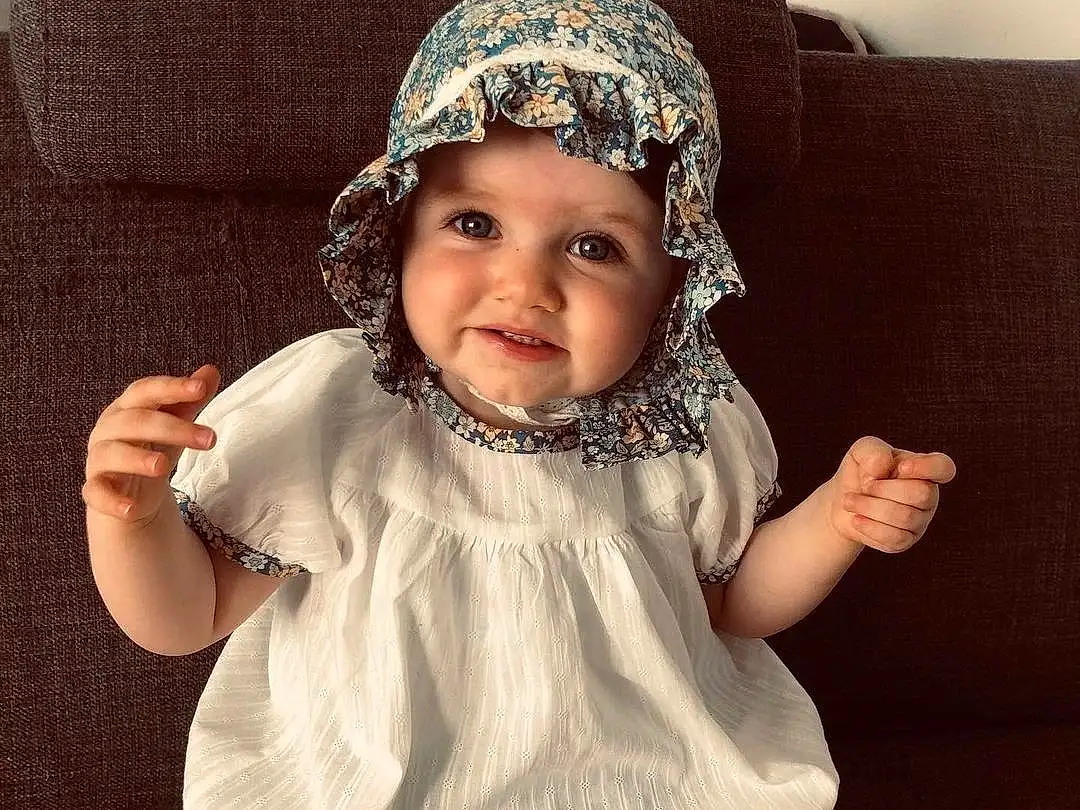 Visage, Sourire, Baby & Toddler Clothing, Human Body, Sleeve, Dress, Cap, Gesture, Happy, Flash Photography, Bambin, Thigh, Thumb, Costume Hat, Selfie, Headpiece, Pattern, Helmet, Baby, Chest, Personne, Joy, Headwear