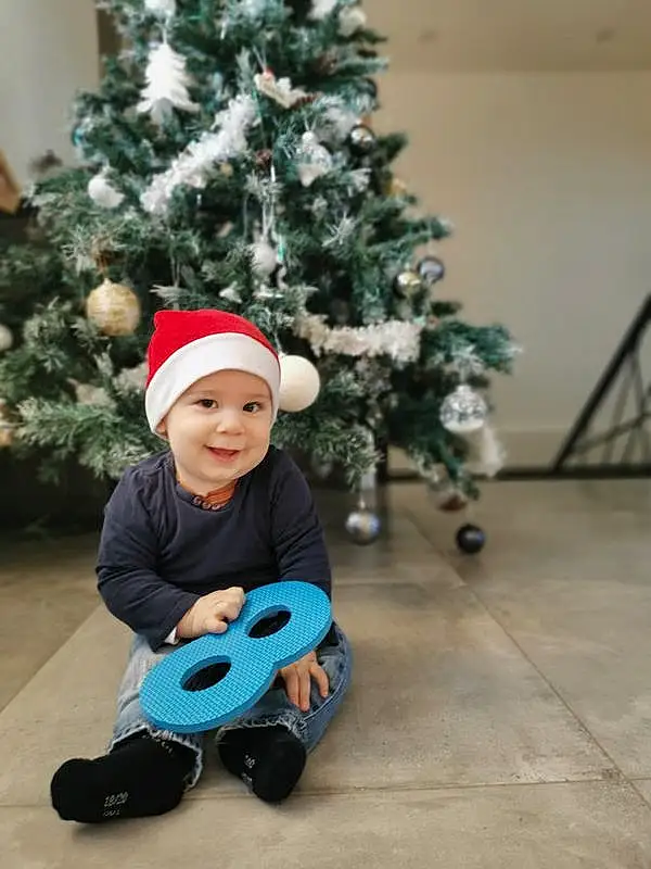 Sourire, Christmas Tree, Facial Expression, Christmas Ornament, Vehicle, Debout, Baby & Toddler Clothing, Tire, Holiday Ornament, Woody Plant, Christmas Decoration, Bambin, Ornament, Happy, Arbre, Fun, Holiday, Event, Wheel, Hiver, Personne, Joy, Headwear
