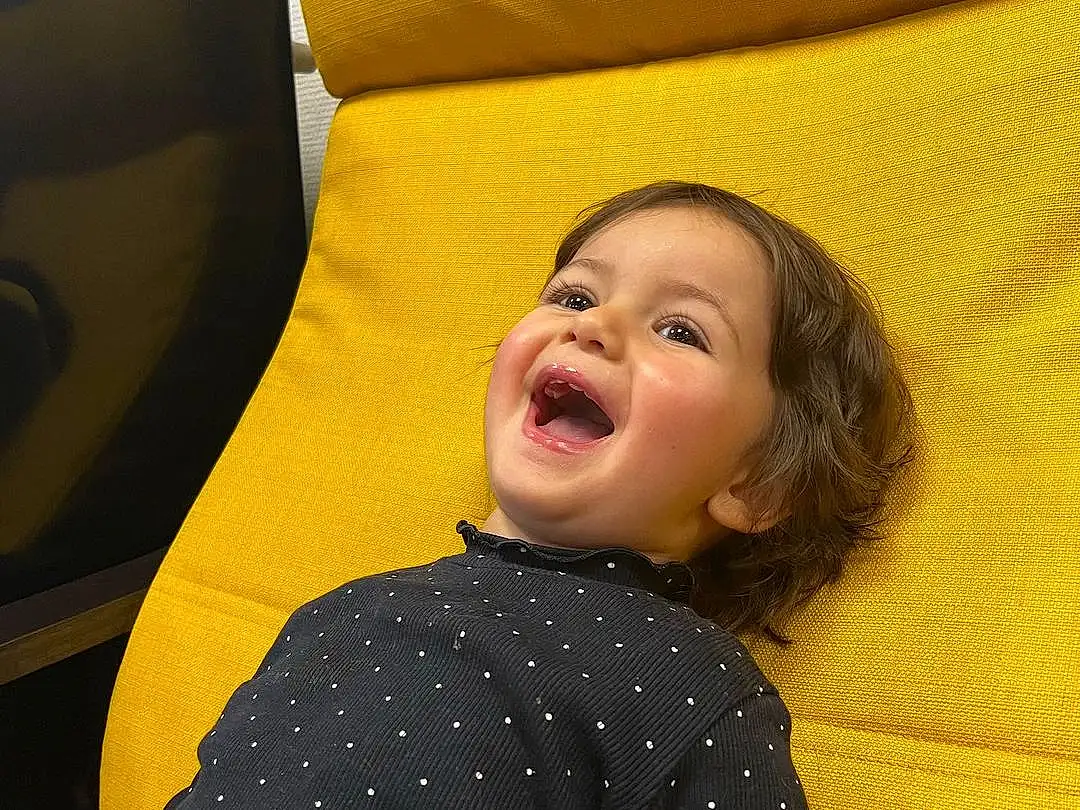 Coiffure, Comfort, Sourire, Textile, Sleeve, Yellow, Baby & Toddler Clothing, Happy, Fun, Rectangle, Bambin, Pattern, Couch, Enfant, Room, Linens, Assis, Laugh, Portrait Photography, Personne