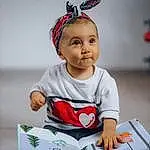 Yeux, Sleeve, Happy, Baby, Book, Bambin, Enfant, Baby & Toddler Clothing, Fun, Assis, Room, Carmine, Sourire, Fashion Accessory, T-shirt, Reading, Portrait Photography, Costume Hat, Personne